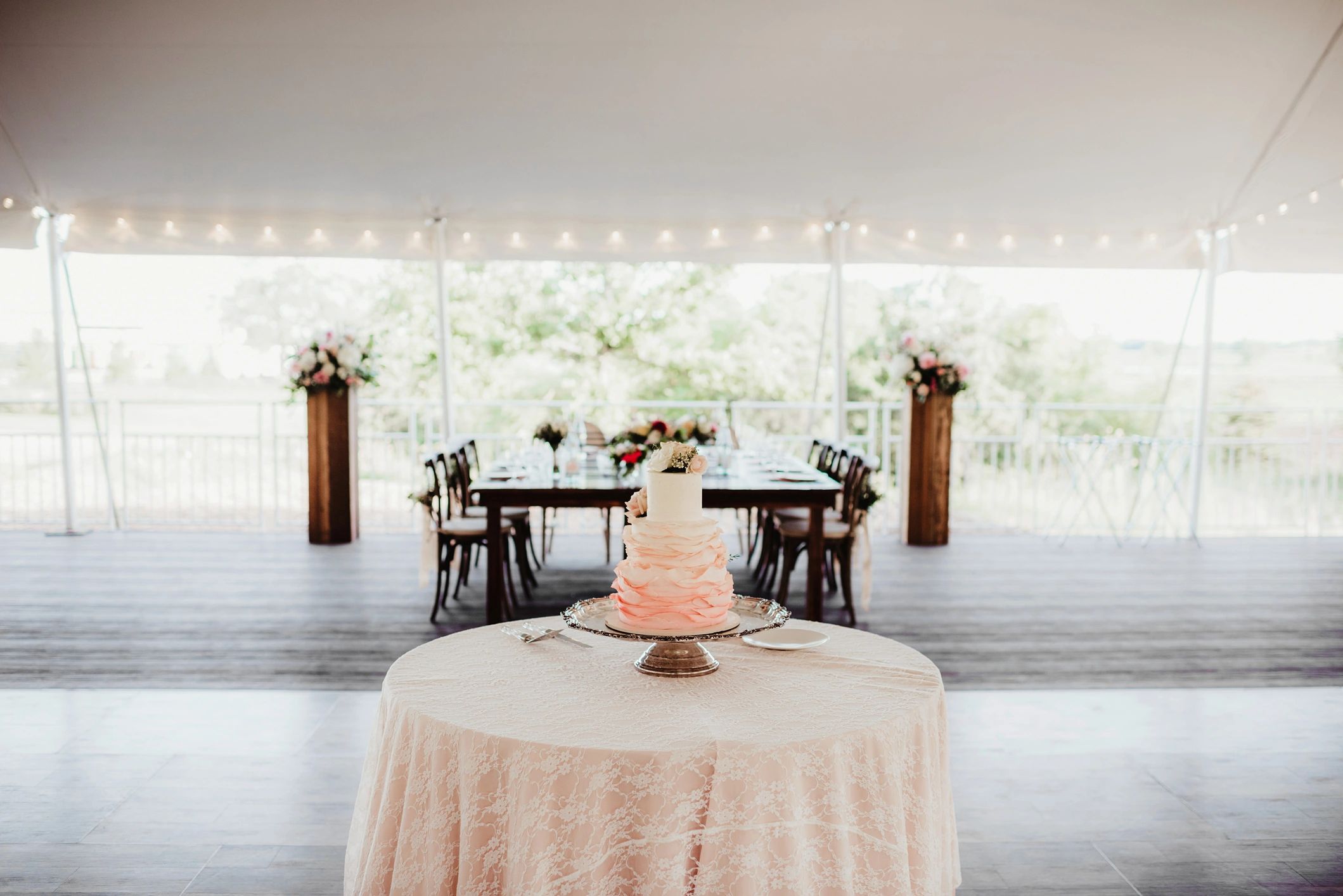 Dessert table with tiered wedding cake in reception tent